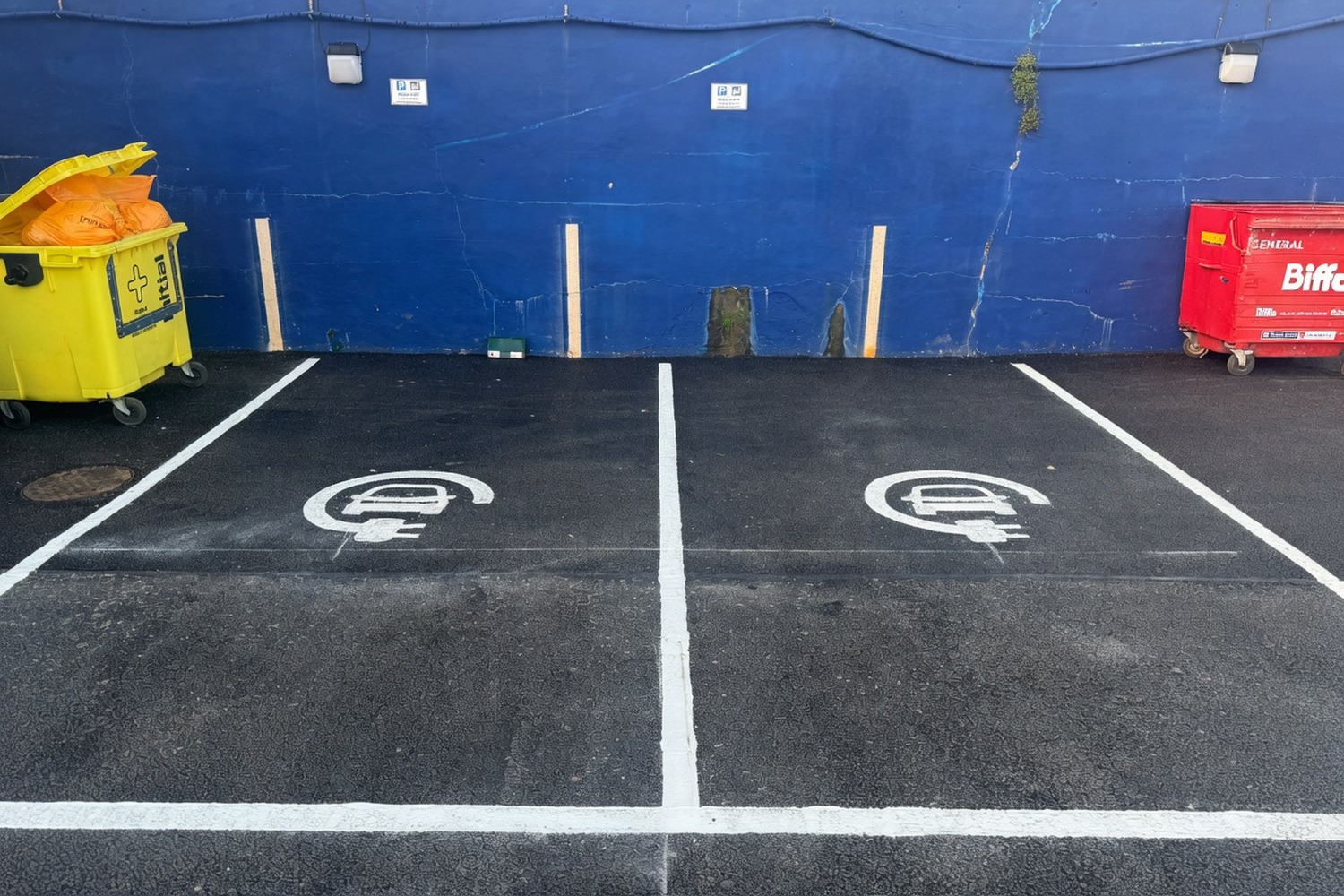 EV charging bays painted along a wall with blue accent line